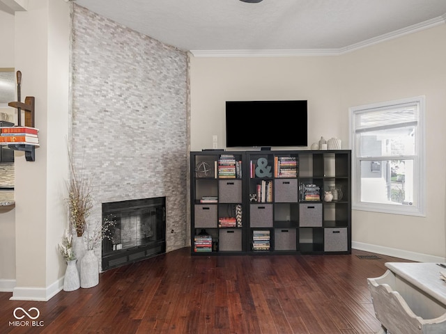 living room with wood-type flooring, crown molding, and a stone fireplace