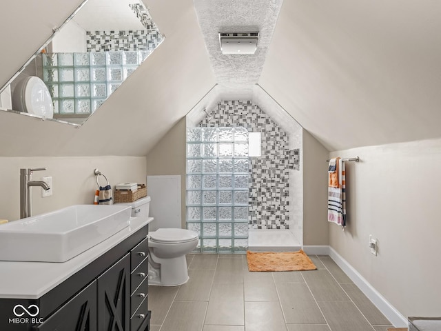 full bathroom with a tile shower, tile patterned flooring, vanity, toilet, and lofted ceiling