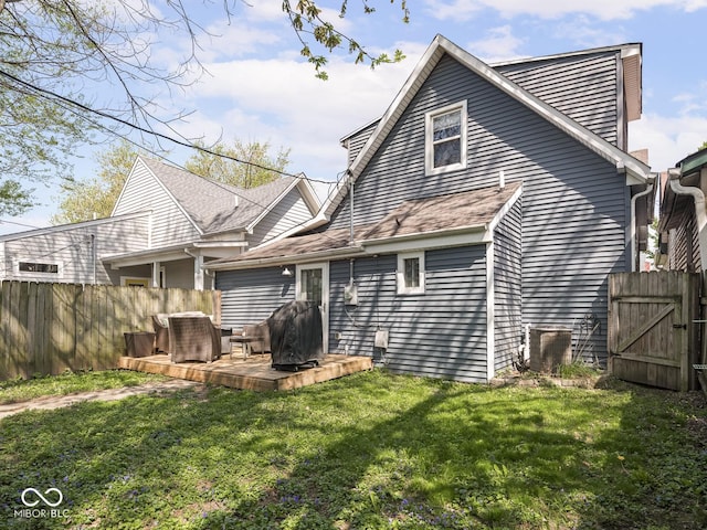 rear view of property featuring fence, a gate, central air condition unit, and a lawn