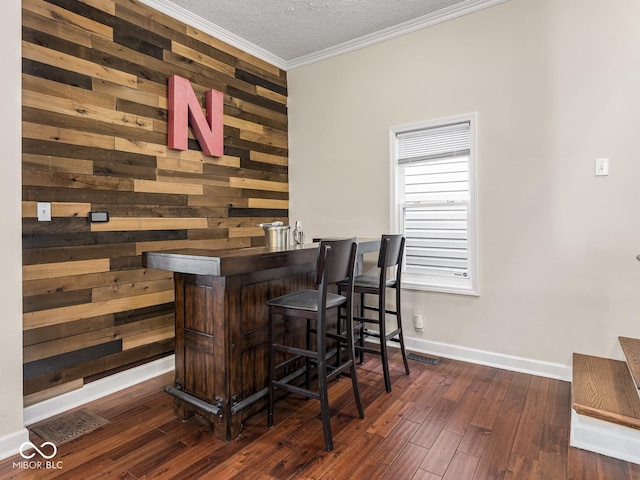bar featuring crown molding, a dry bar, wood walls, baseboards, and wood-type flooring