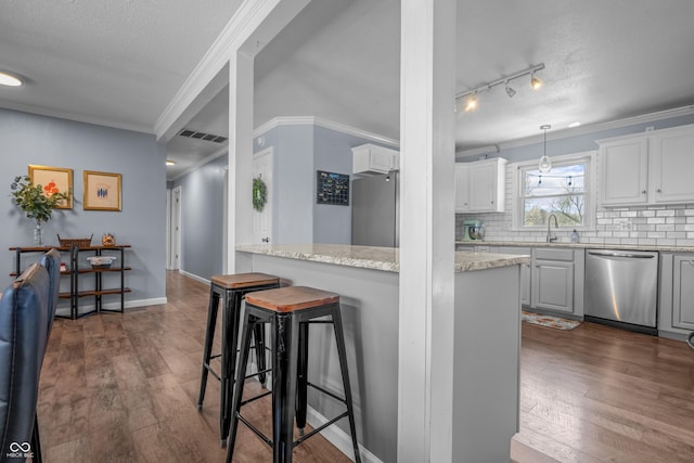 kitchen with stainless steel appliances, ornamental molding, a breakfast bar area, and dark wood finished floors