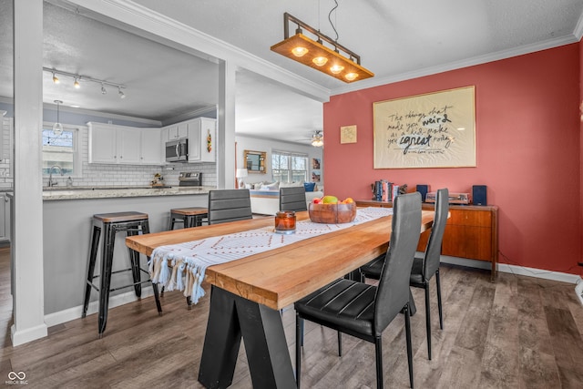 dining room featuring wood finished floors, crown molding, baseboards, and ceiling fan
