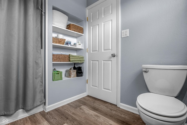full bath with baseboards, wood finished floors, and toilet