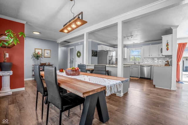 dining area with baseboards, ornamental molding, dark wood-type flooring, and a textured ceiling