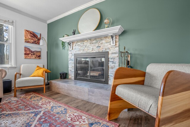 sitting room featuring a fireplace, wood finished floors, and crown molding