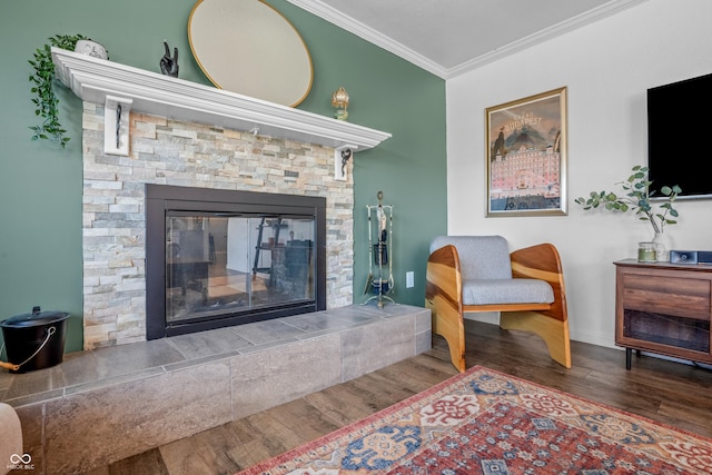 living area with a fireplace, wood finished floors, baseboards, and ornamental molding
