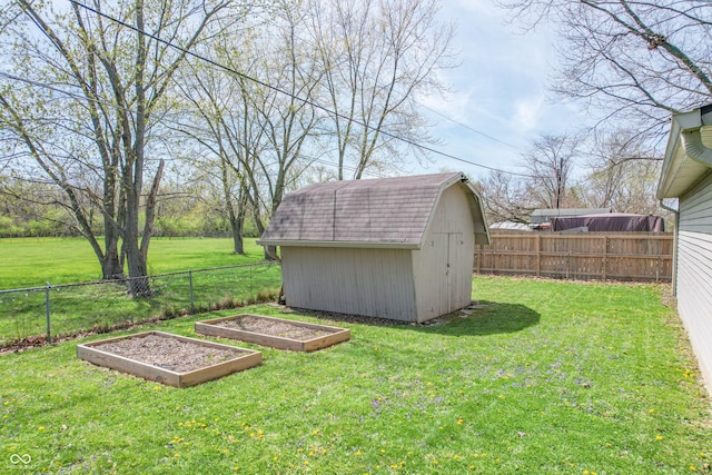 view of yard with a storage shed, a garden, a fenced backyard, and an outdoor structure