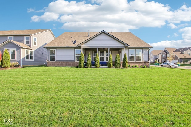 rear view of property with a ceiling fan, a yard, brick siding, and a sunroom