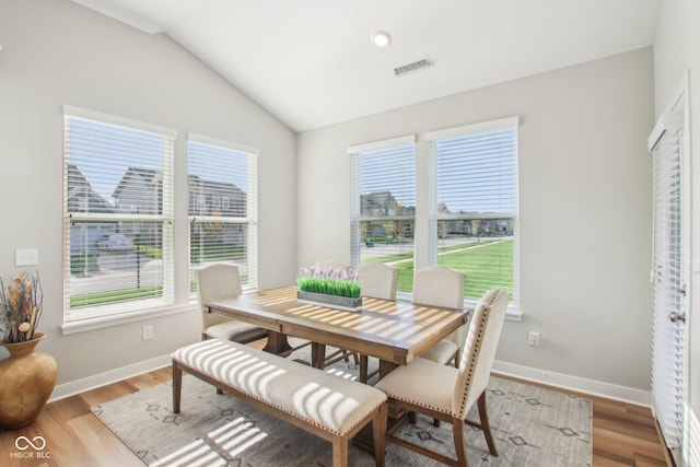dining room with light wood finished floors, visible vents, lofted ceiling, and plenty of natural light