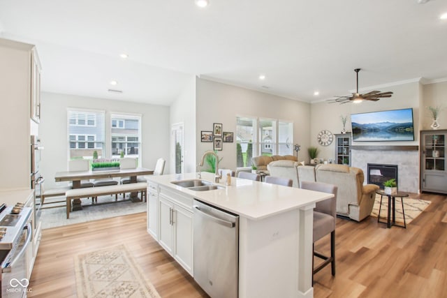 kitchen featuring a sink, light wood-style floors, a breakfast bar area, dishwasher, and an island with sink