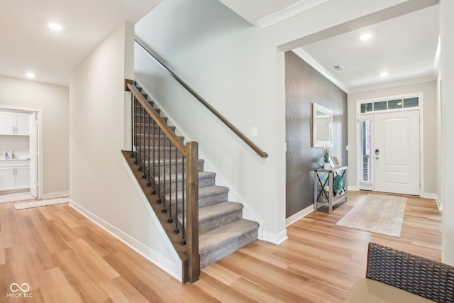 foyer entrance with baseboards, stairs, light wood-style floors, and ornamental molding