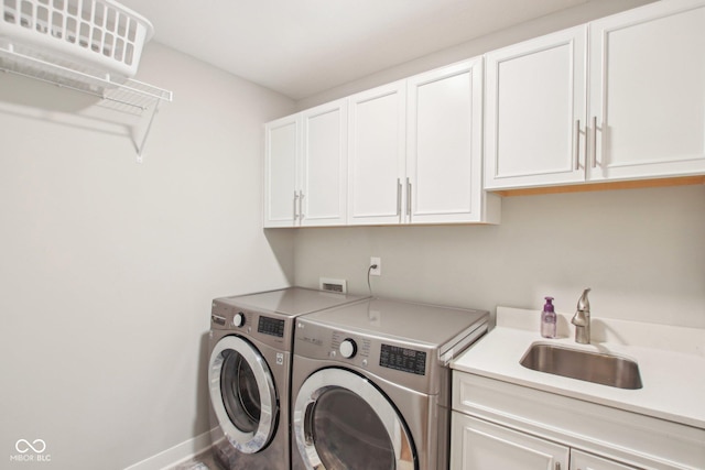 laundry area with a sink, washer and dryer, cabinet space, and baseboards