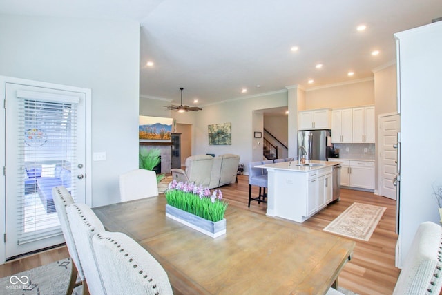 dining space with ornamental molding, a healthy amount of sunlight, stairway, and light wood-type flooring