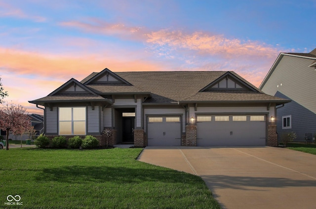 view of front of home with driveway, a shingled roof, an attached garage, a lawn, and brick siding
