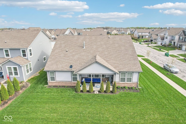 rear view of property with brick siding, a residential view, a shingled roof, and a yard