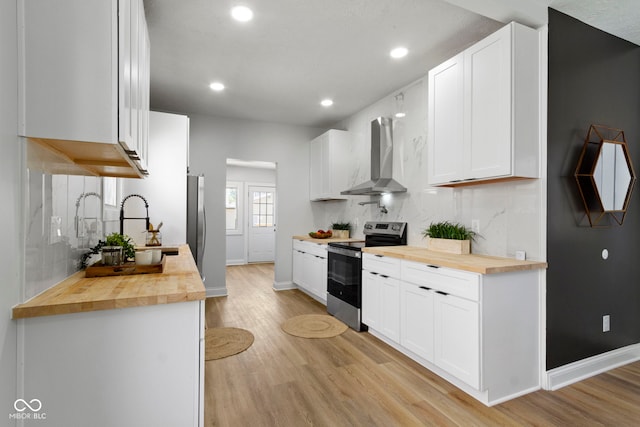 2005 Carrollton Ave, Indianapolis, IN 46202 - kitchen featuring electric stove, butcher block countertops, wall chimney range hood, light wood-type flooring, and a sink