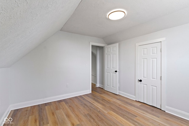 2005 Carrollton Ave, Indianapolis, IN 46202 - additional living space featuring light wood-style floors, lofted ceiling, baseboards, and a textured ceiling