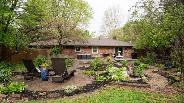 rear view of property featuring brick siding, a patio area, fence, and a chimney