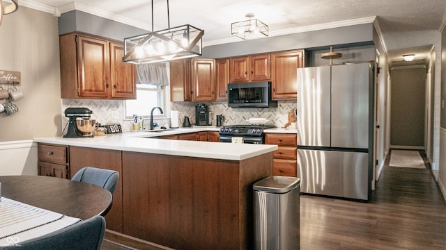 kitchen featuring appliances with stainless steel finishes, brown cabinets, light countertops, a peninsula, and dark wood-style floors