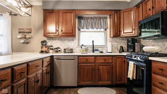 kitchen featuring stainless steel dishwasher, light countertops, a sink, and black gas stove