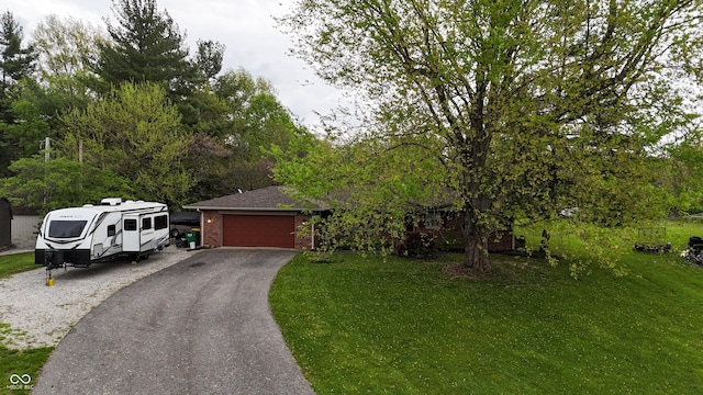 view of property hidden behind natural elements featuring brick siding, a front lawn, an attached garage, and driveway