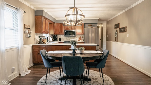 dining space with a wainscoted wall, an inviting chandelier, a healthy amount of sunlight, and dark wood-type flooring