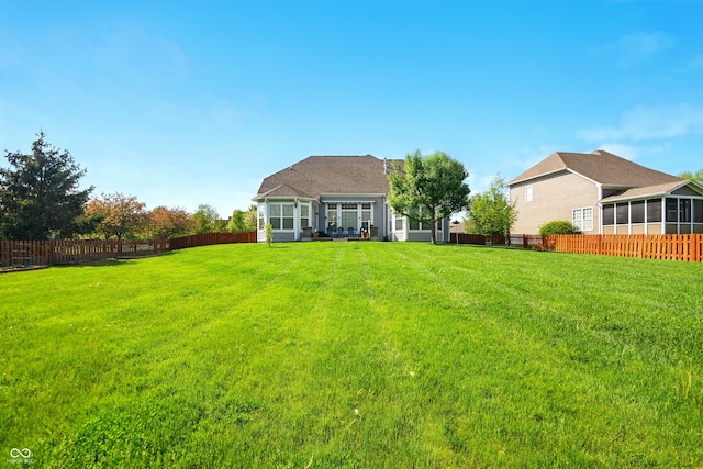 back of property featuring a fenced backyard, a lawn, and a sunroom