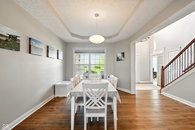 dining room featuring baseboards, a raised ceiling, wood finished floors, and stairway