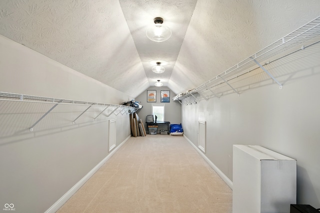 spacious closet with light colored carpet and lofted ceiling