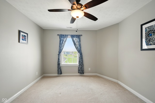 carpeted spare room with baseboards, ceiling fan, a textured ceiling, and visible vents