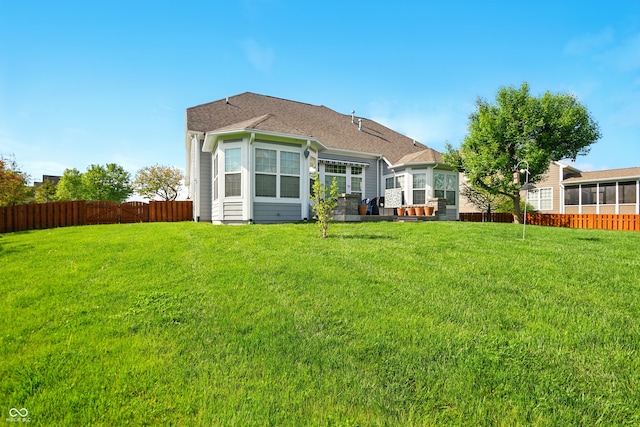 rear view of house featuring a yard and fence