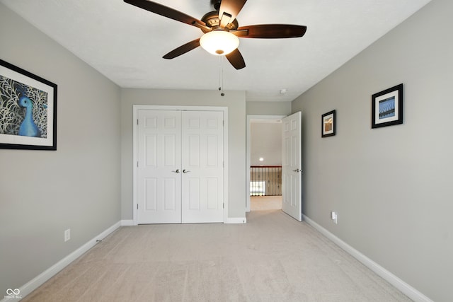 unfurnished bedroom with a ceiling fan, baseboards, light carpet, and a closet