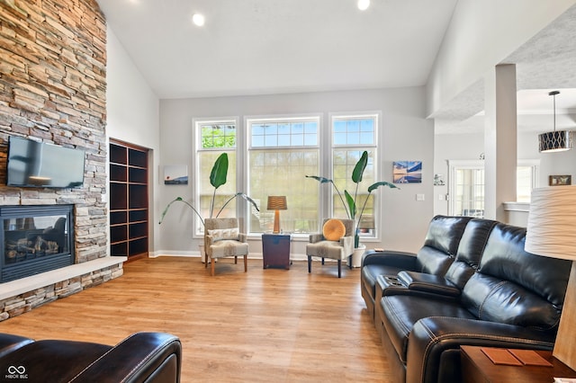 living area featuring recessed lighting, baseboards, light wood finished floors, and a stone fireplace