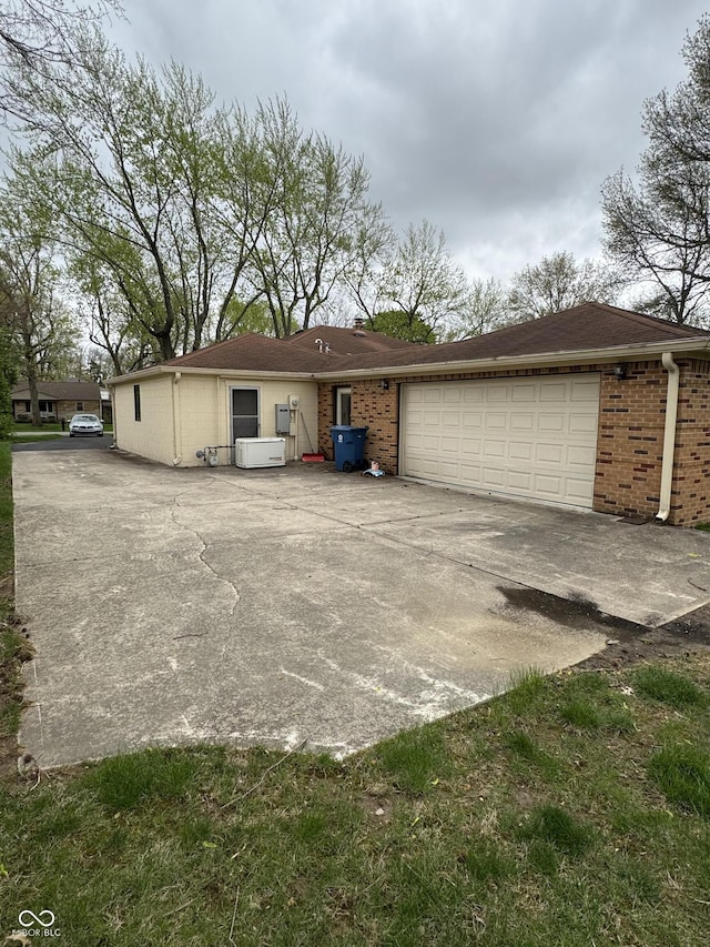 exterior space featuring concrete driveway, an attached garage, and brick siding