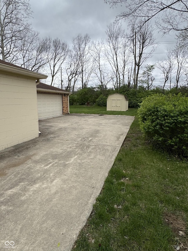 view of patio / terrace featuring an outbuilding, a storage shed, and a garage