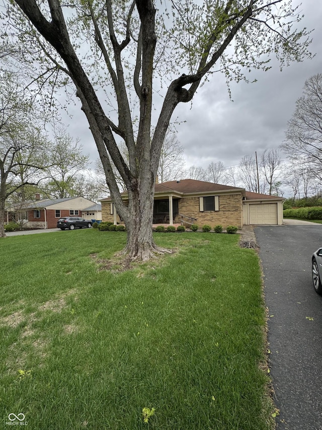 ranch-style home with brick siding, an attached garage, a front lawn, and driveway