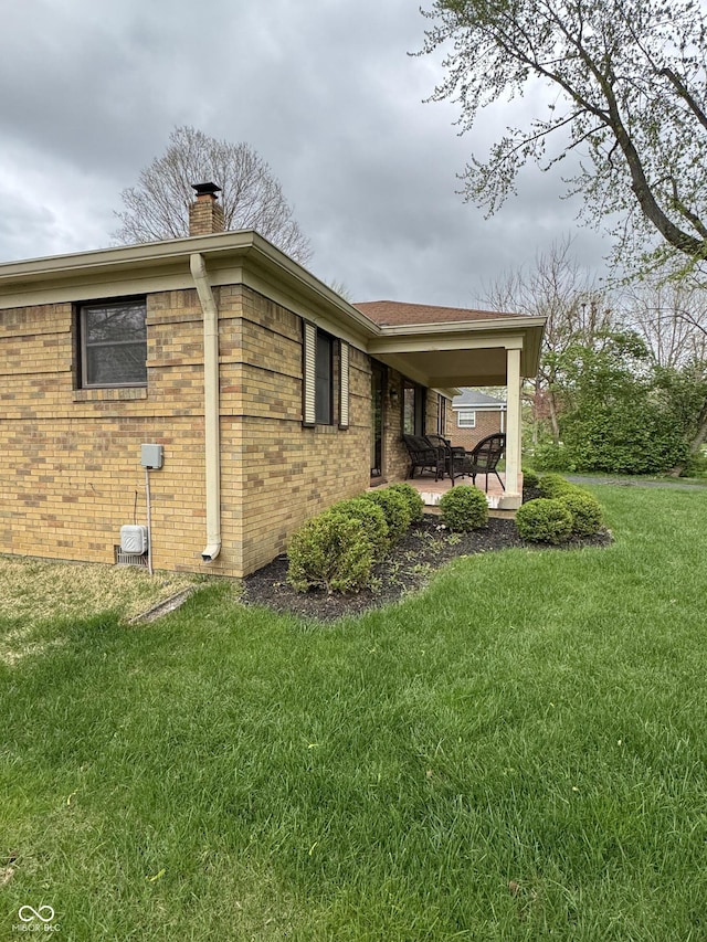 view of home's exterior with a lawn, a chimney, and brick siding