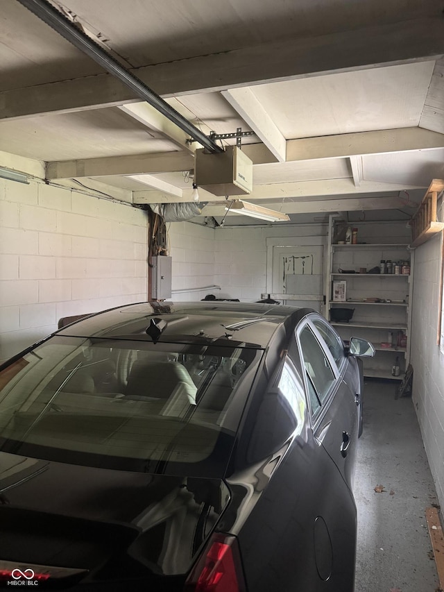 garage featuring electric panel, concrete block wall, and a garage door opener