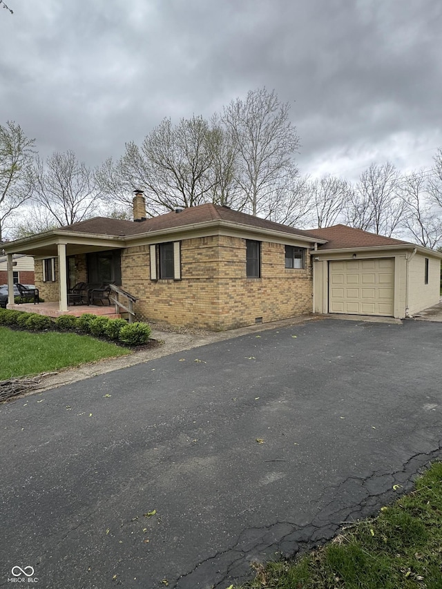 view of front of house with brick siding, an attached garage, driveway, and a chimney