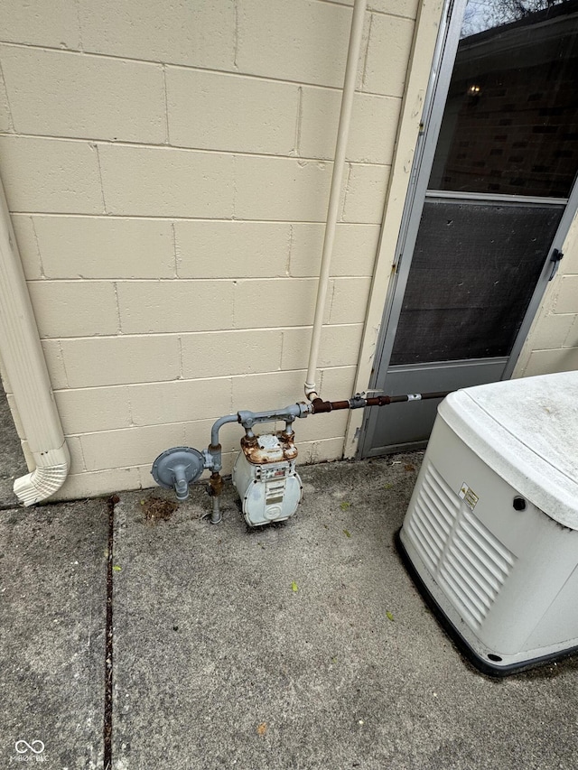 details with gas meter, concrete block siding, and a power unit