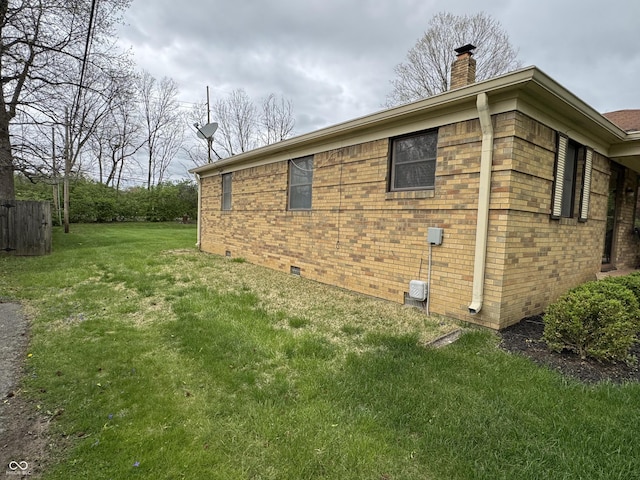 view of side of property with brick siding, a lawn, crawl space, and a chimney