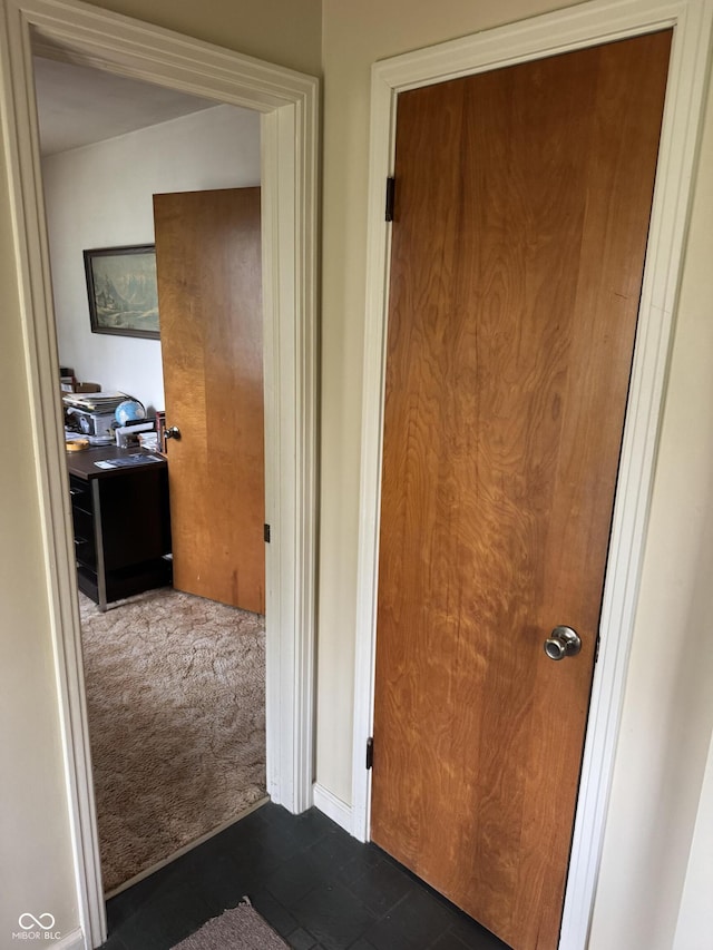 corridor featuring dark carpet and dark tile patterned flooring