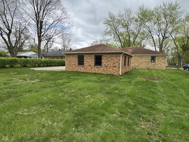 exterior space with brick siding and a yard