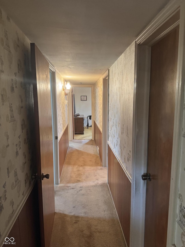 corridor featuring wallpapered walls and light colored carpet