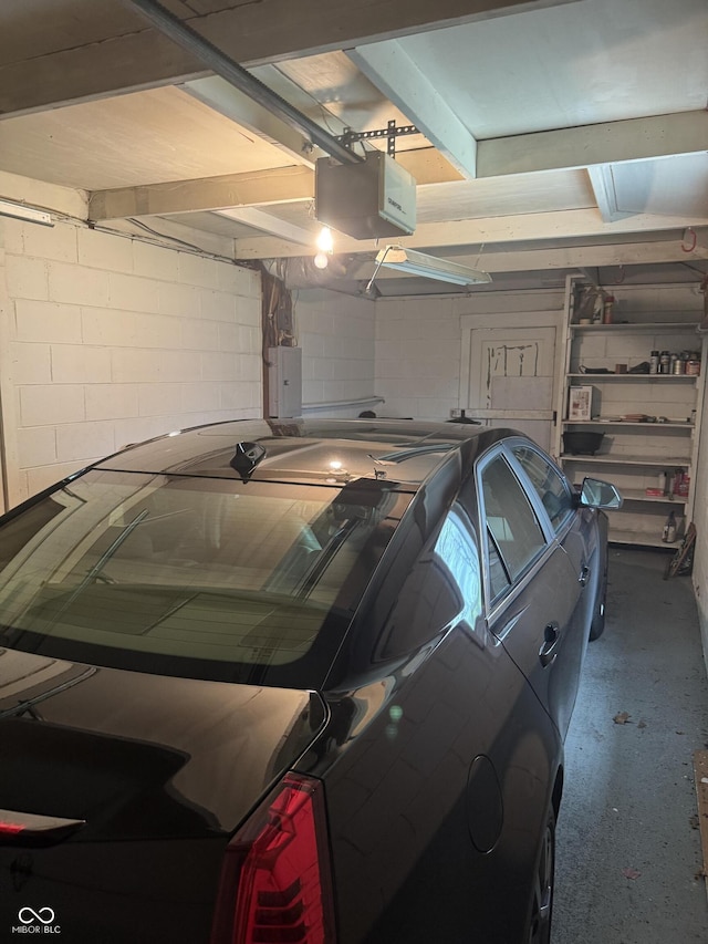 garage with concrete block wall, electric panel, and a garage door opener