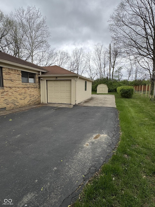 view of side of home featuring brick siding, aphalt driveway, a storage shed, and a garage