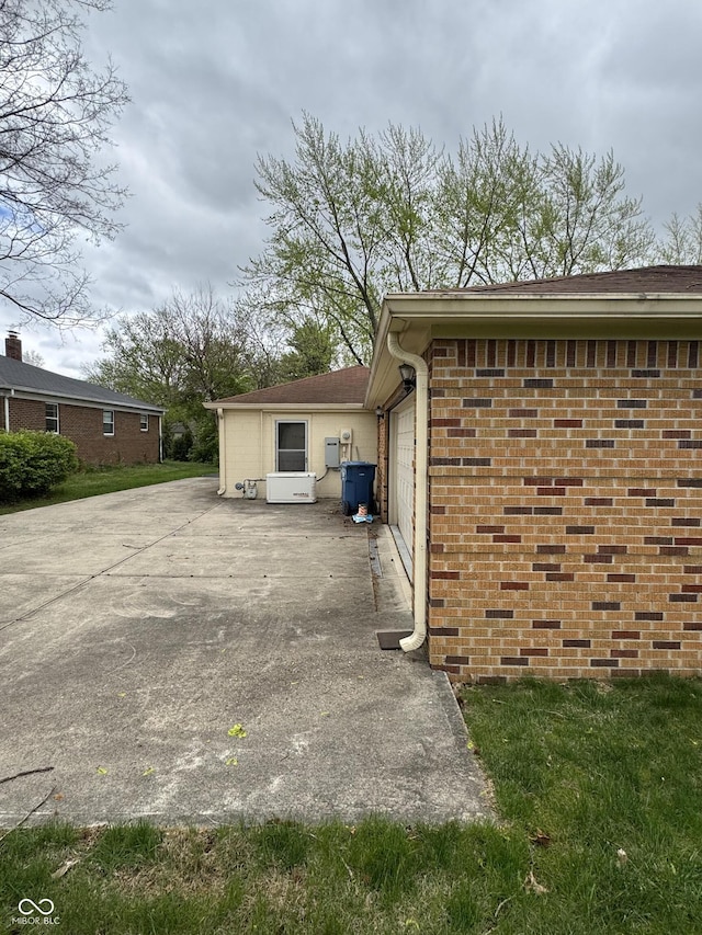 view of property exterior with brick siding and a garage