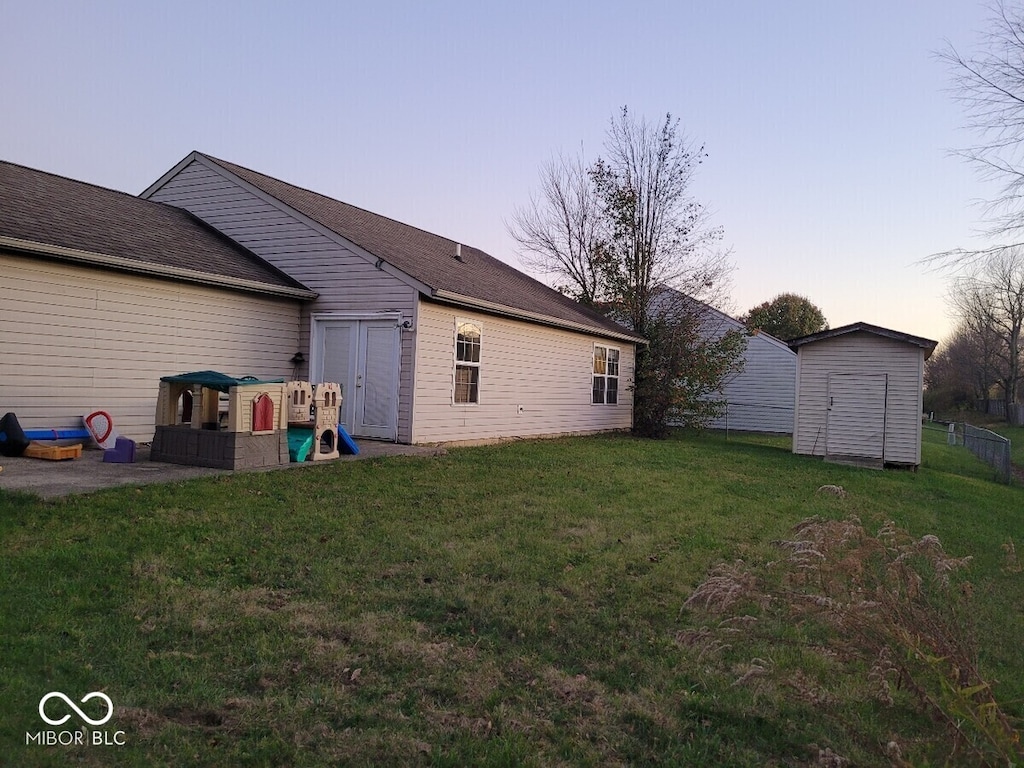 back of property at dusk with an outdoor structure, a shed, and a yard