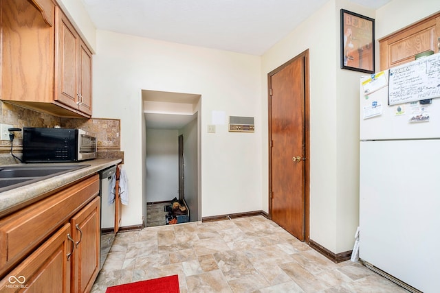 kitchen featuring freestanding refrigerator, dishwasher, baseboards, backsplash, and light countertops