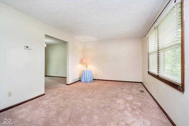 empty room featuring baseboards, visible vents, and carpet floors